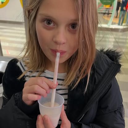 Girl sipping milk from a cup through a straw