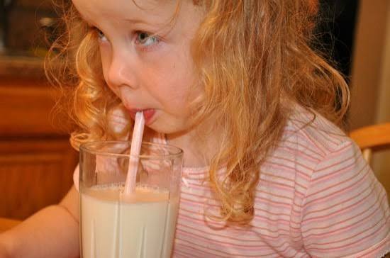 Toddler sipping milk through a pink straw