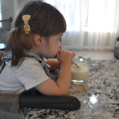 Toddler reaching for a glass of milk